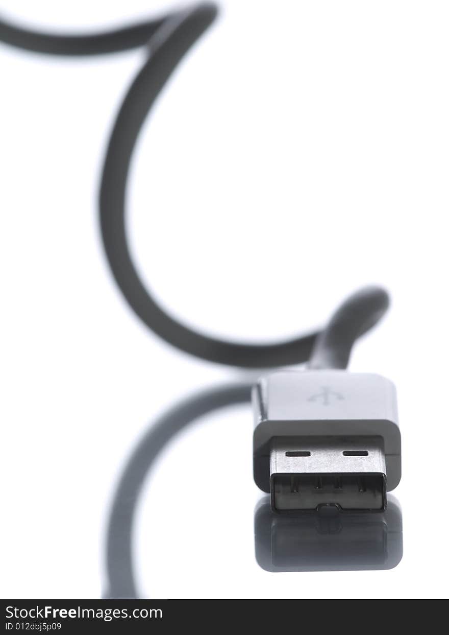 An USB connection facing camera with its cable curling and reflecting behind out of focus. An USB connection facing camera with its cable curling and reflecting behind out of focus.