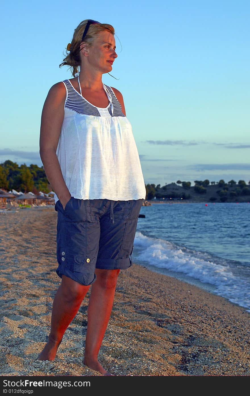 Woman stands on the beach and watches sunset. Woman stands on the beach and watches sunset