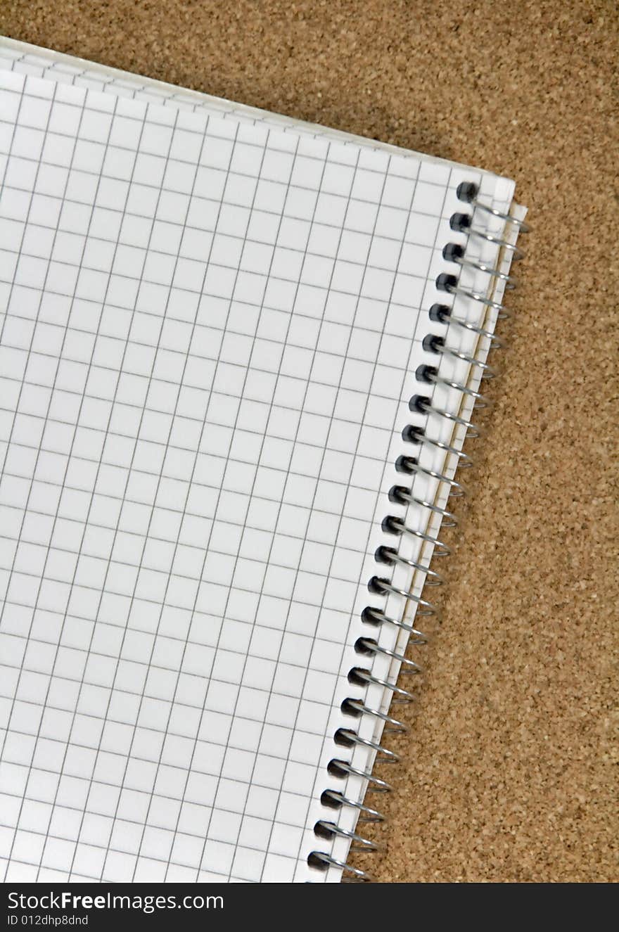 Spiral ring bound notepad on corkboard background