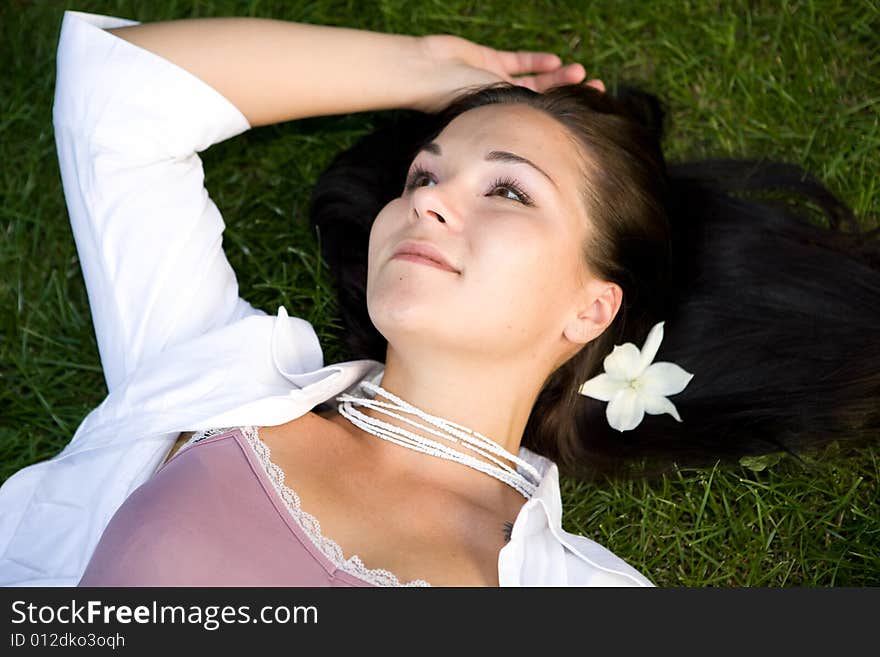 Attractive brunette woman lying on grass. Attractive brunette woman lying on grass