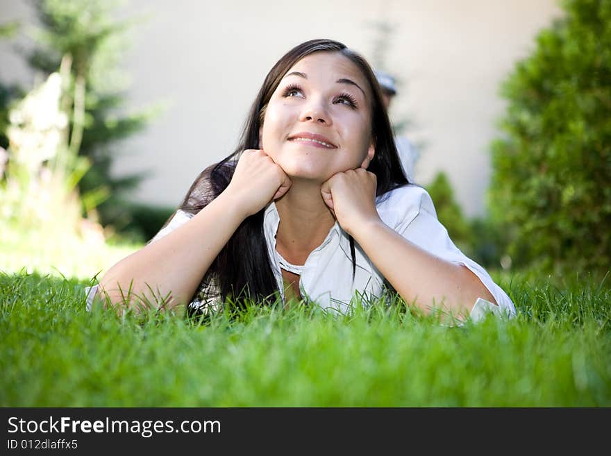 Attractive brunette woman lying on grass. Attractive brunette woman lying on grass