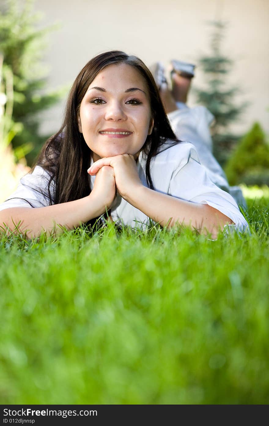 Attractive brunette woman lying on grass. Attractive brunette woman lying on grass