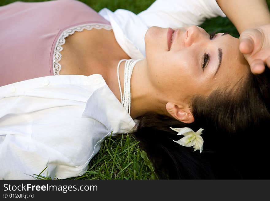 Attractive brunette woman lying on grass. Attractive brunette woman lying on grass