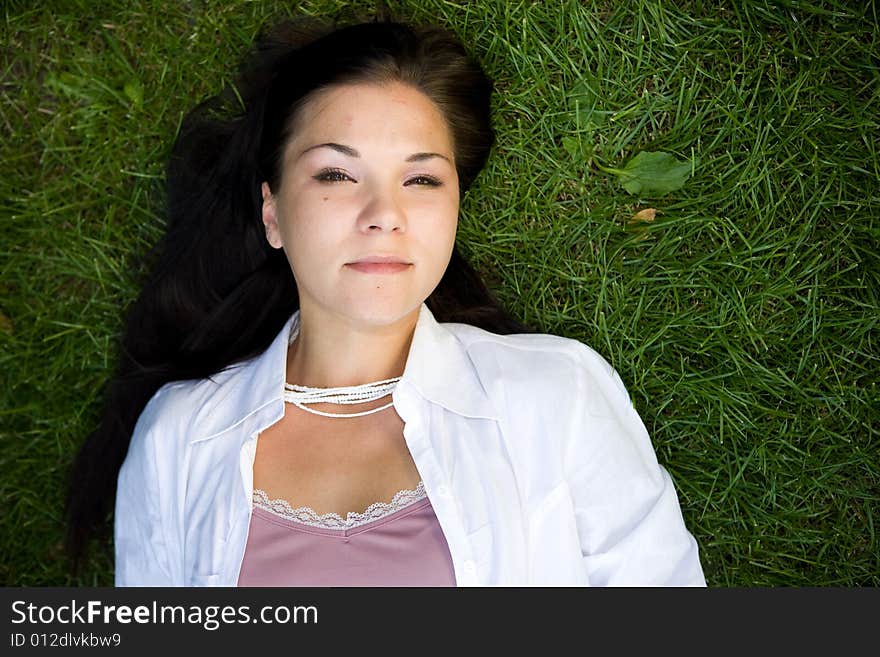 Attractive brunette woman lying on grass. Attractive brunette woman lying on grass