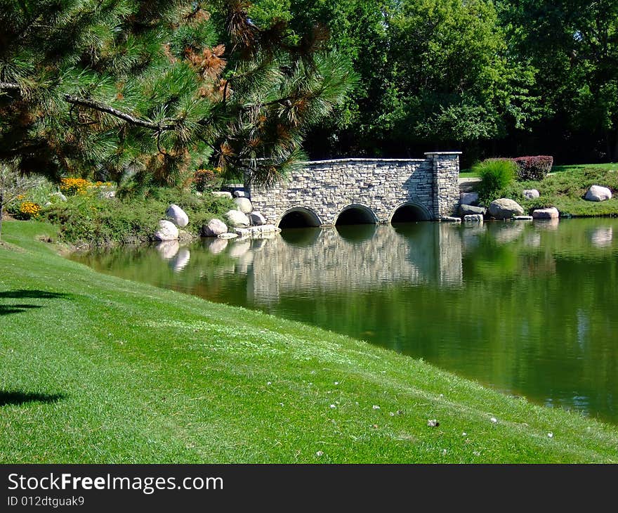 A still lake reflecting a mirror image of a bridge. A still lake reflecting a mirror image of a bridge.