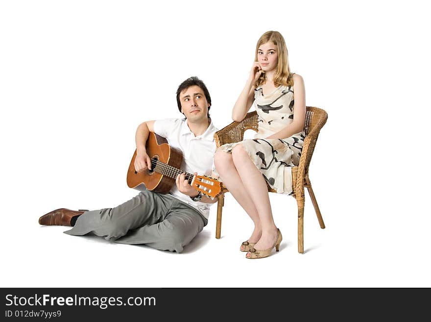 A blond girl and a man playing guitar for her. A blond girl and a man playing guitar for her