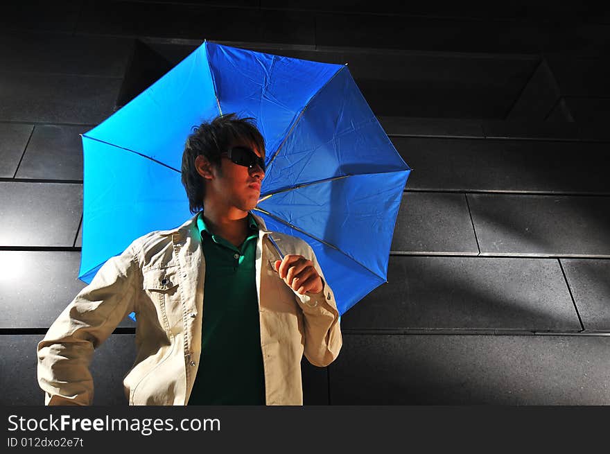 Picture of a male model with a dark background and blue umbrella. Picture of a male model with a dark background and blue umbrella.