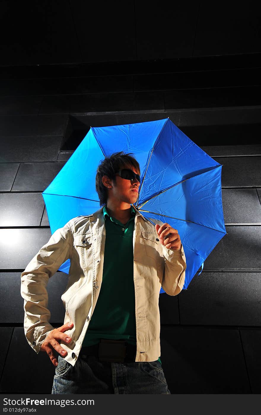 Picture of a male model with a dark background and blue umbrella. Picture of a male model with a dark background and blue umbrella.