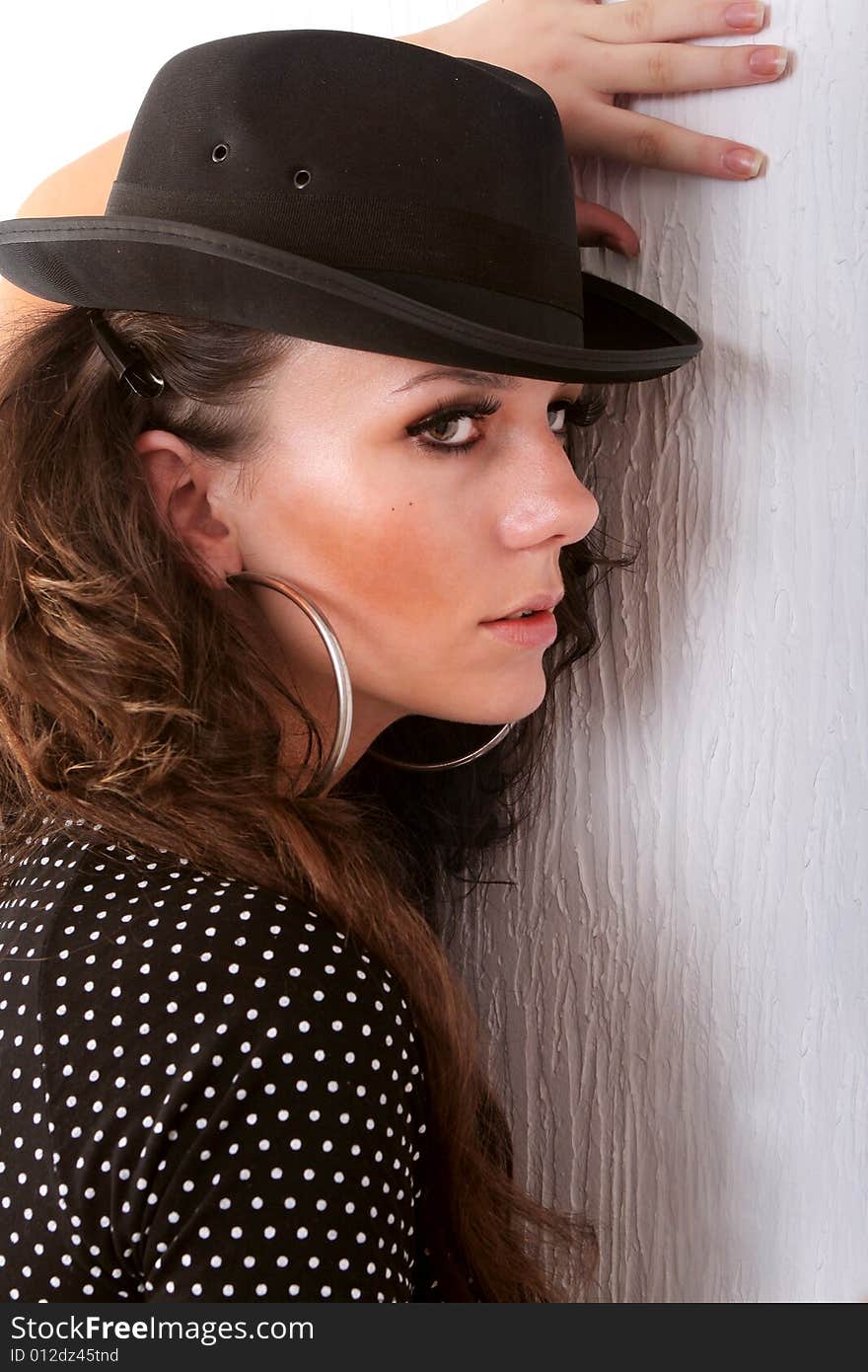 Beautiful female close to wall with hat on her head. Beautiful female close to wall with hat on her head