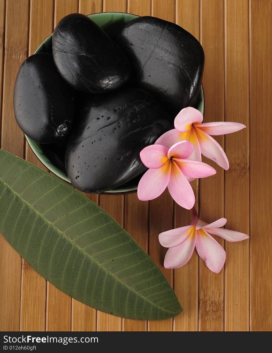 A composition of black stone for massage, aromatic candle and flowers. A composition of black stone for massage, aromatic candle and flowers