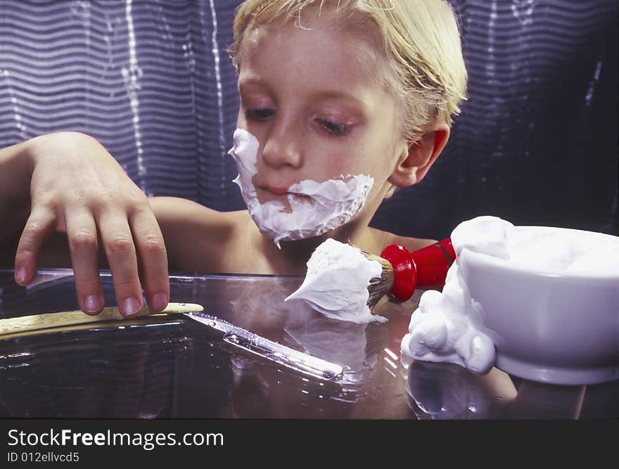 Young boy with razor shaving