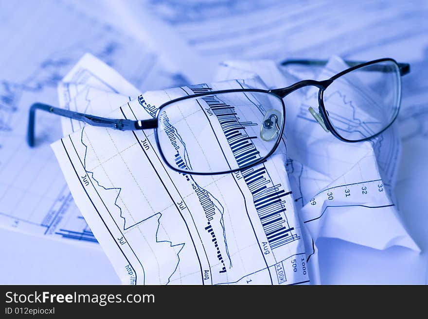 Crumpled paper with glasses - imitating tiredness of financial data. Crumpled paper with glasses - imitating tiredness of financial data