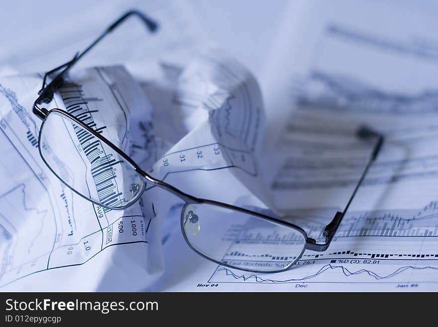 Crumpled paper with glasses - imitating tiredness of financial data. Crumpled paper with glasses - imitating tiredness of financial data