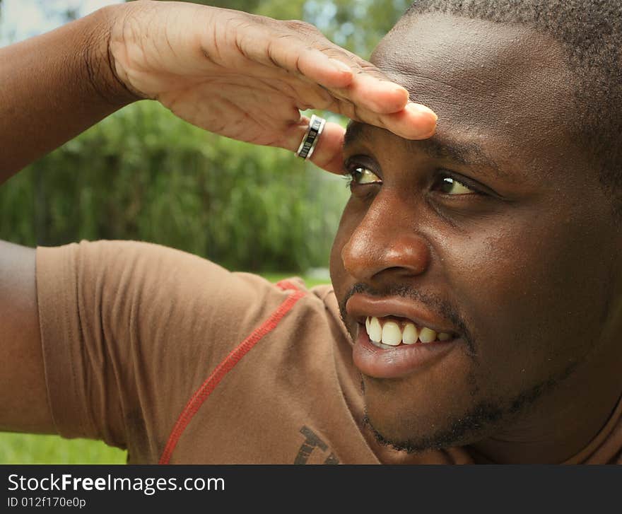 Man watching something with his hand on his forehead to block the light.