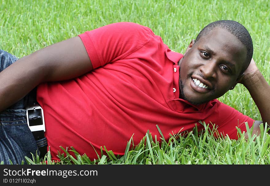 Young black man laying on green grass. Young black man laying on green grass.