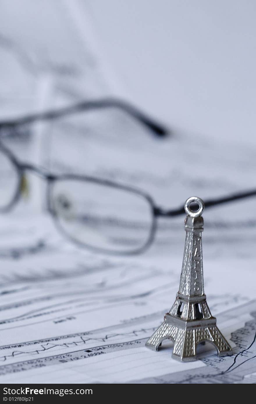 Eiffel tower on a chart. Glasses seen in the background. Shallow depth of field. Eiffel tower on a chart. Glasses seen in the background. Shallow depth of field.