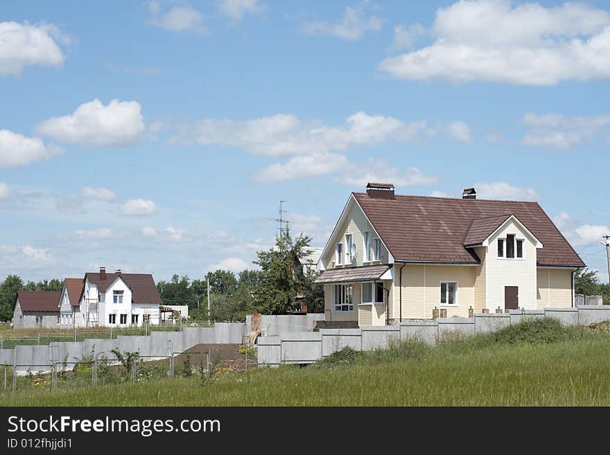 New houses surrounded with a green grass against the blue sky with clouds