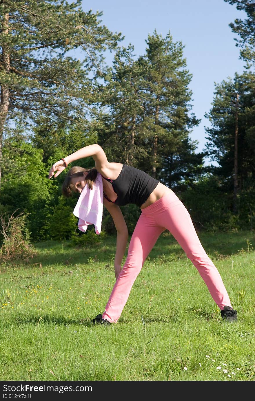 Young girl doing gymnastics in the nature with towel around neck. Young girl doing gymnastics in the nature with towel around neck