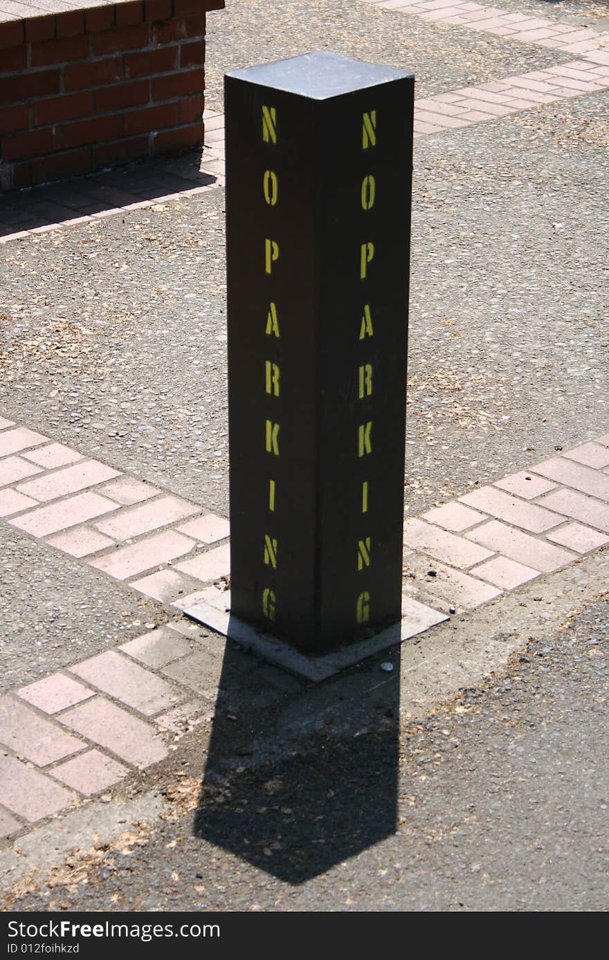 A No Parking sign painted on a steel pillar.