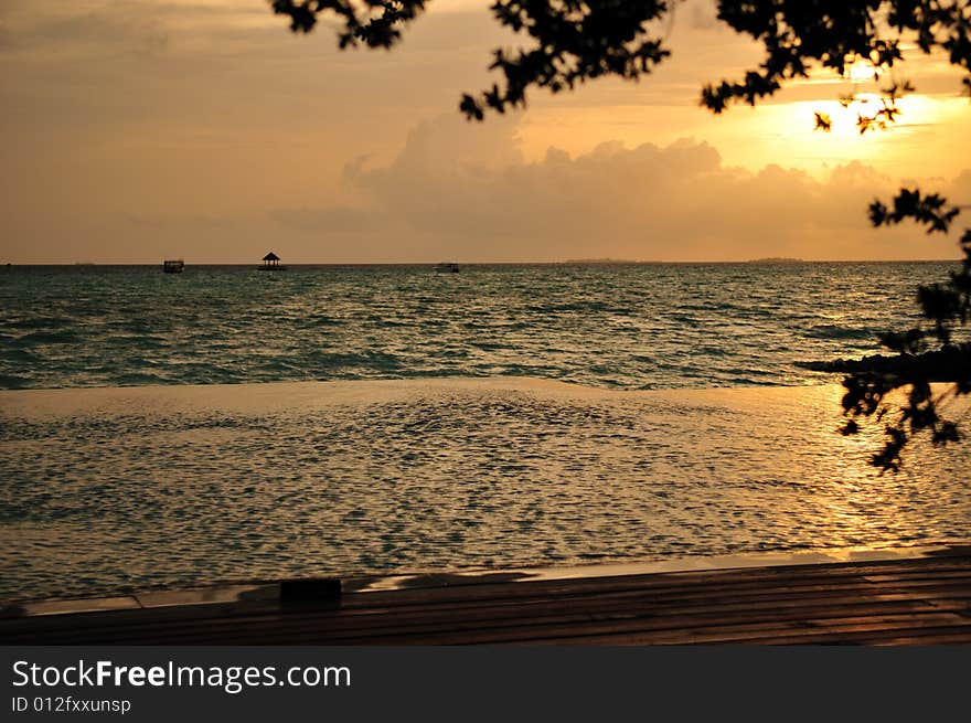 Small wave gently swapping on golden tropical beach. in the background a great sunrise or sunset is taking place. Small wave gently swapping on golden tropical beach. in the background a great sunrise or sunset is taking place.