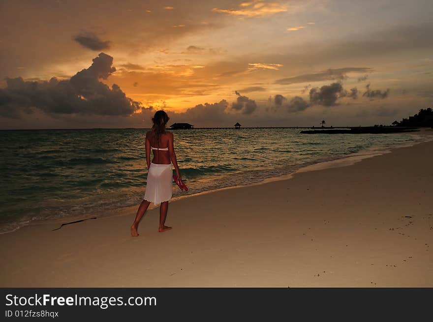 Woman wearing a flowing white sarong on a tropical beach. Woman wearing a flowing white sarong on a tropical beach