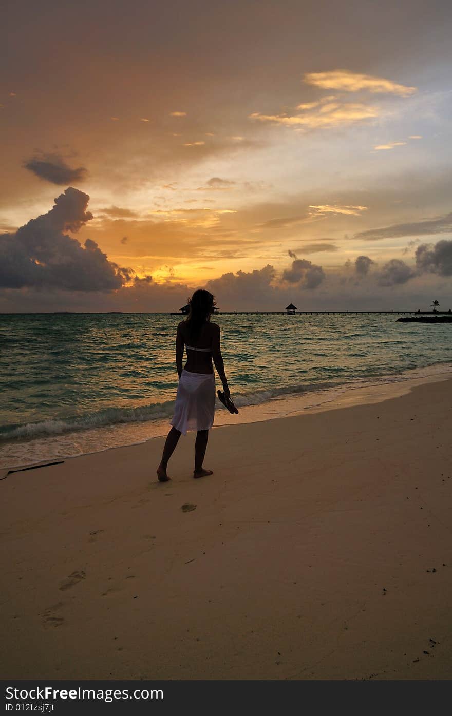 Woman wearing a flowing white sarong on a tropical beach. Woman wearing a flowing white sarong on a tropical beach