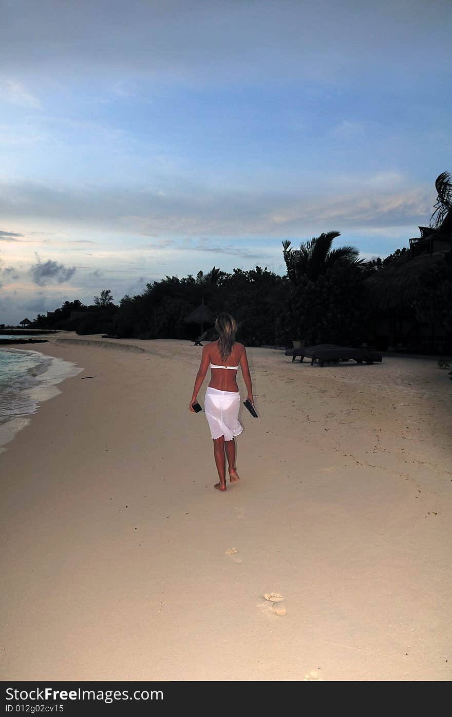 Woman wearing a flowing white sarong on a tropical beach. Woman wearing a flowing white sarong on a tropical beach