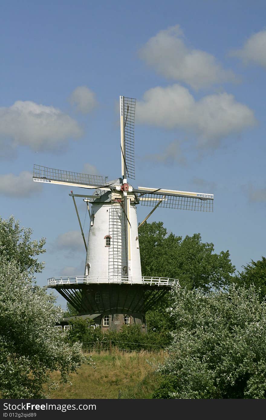 A white windmill with a cloudy sky