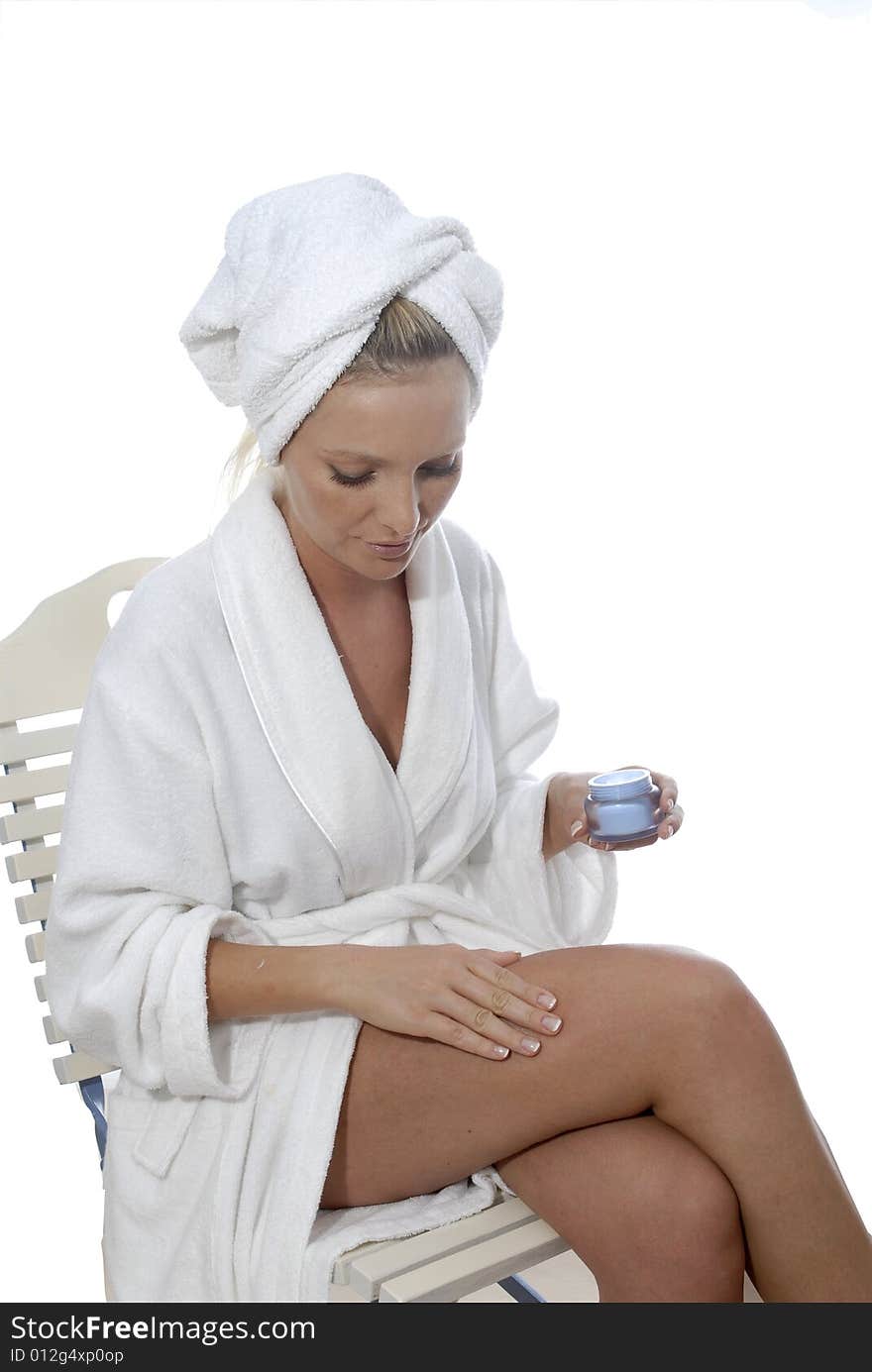 Young woman in spa area applying skin creme. Young woman in spa area applying skin creme.