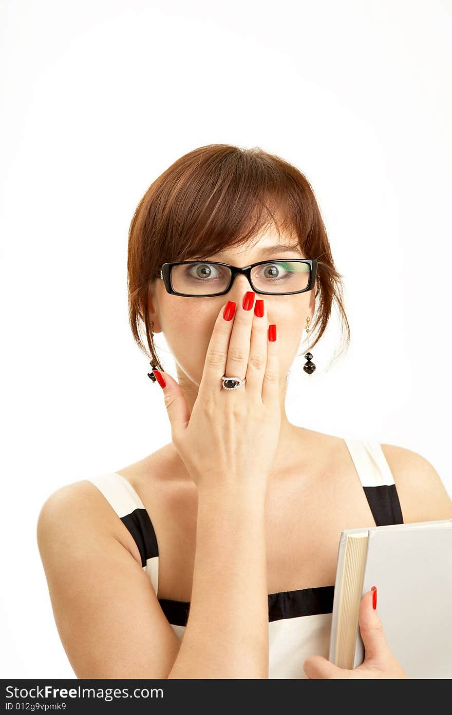 The surprised girl in glasses has covered a face with a hand, other hand holds the book, on a white background