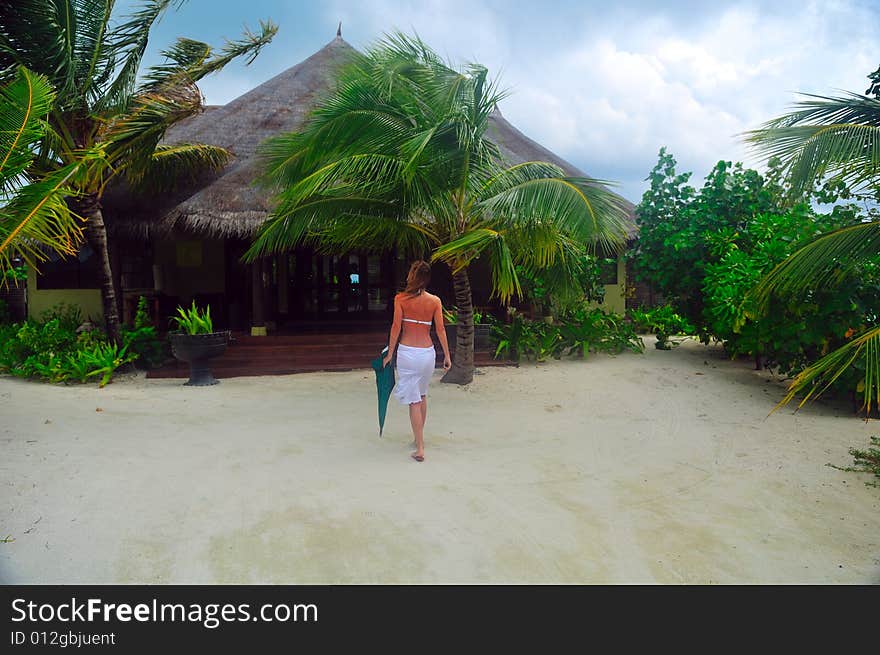 Single woman in calmness going to her bungalow. Luxury Maldives. Single woman in calmness going to her bungalow. Luxury Maldives