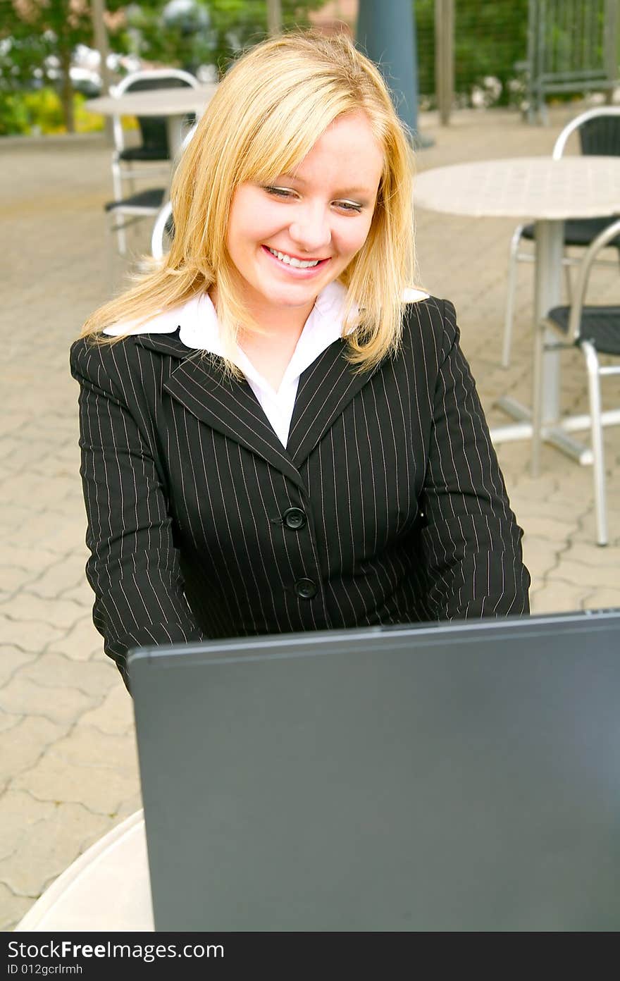 Smiling and happy blond business woman using laptop in modern cafe setting. Smiling and happy blond business woman using laptop in modern cafe setting