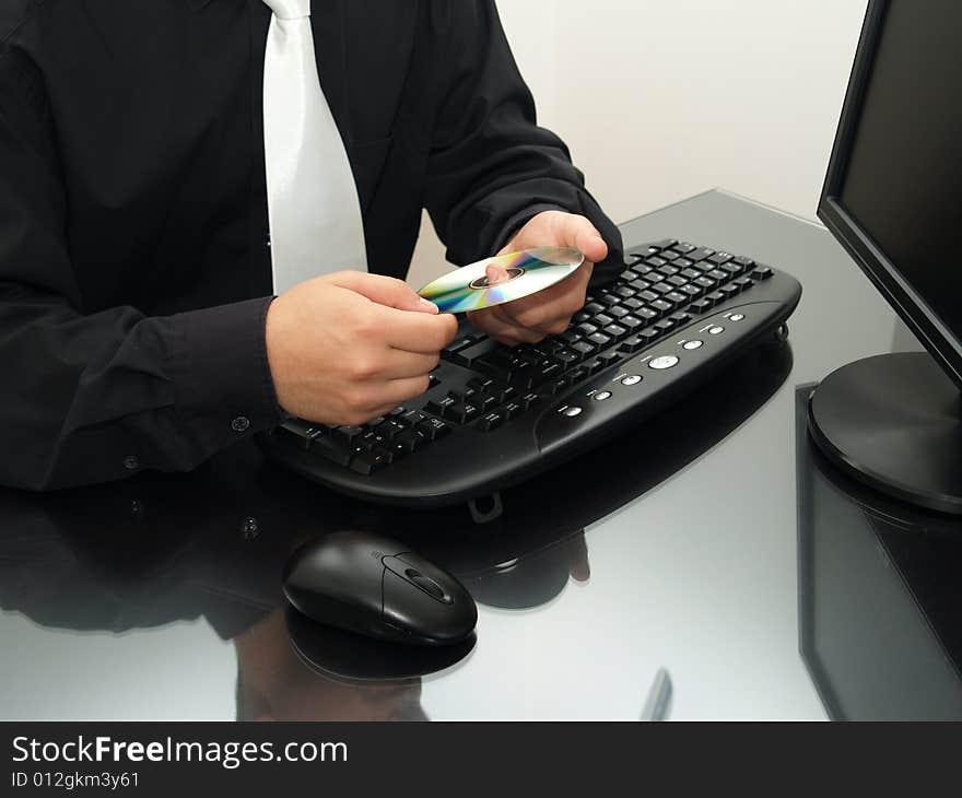 Businessman in front of a computer, holding a disc