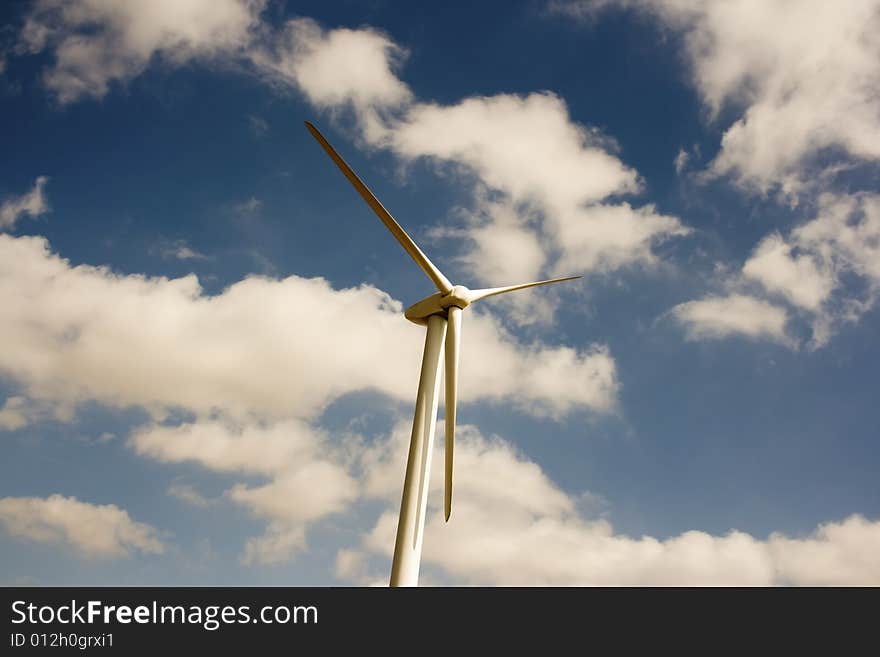 A windmill in the middle of an Iowa field of corn.