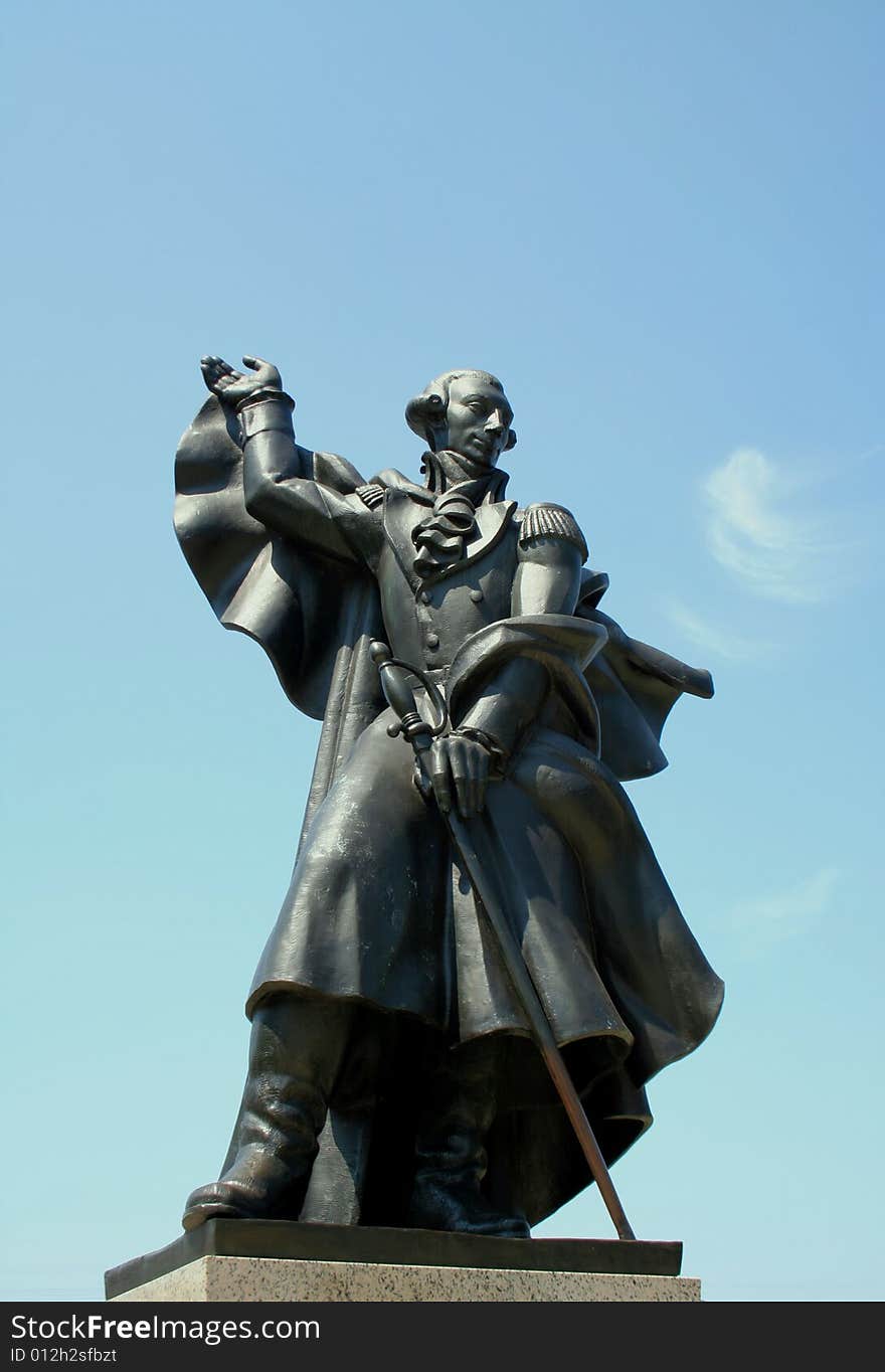 A gray and silver bronze statue of Major General Marquis De Lafayette against a blue sky with a small brush of clouds. A gray and silver bronze statue of Major General Marquis De Lafayette against a blue sky with a small brush of clouds