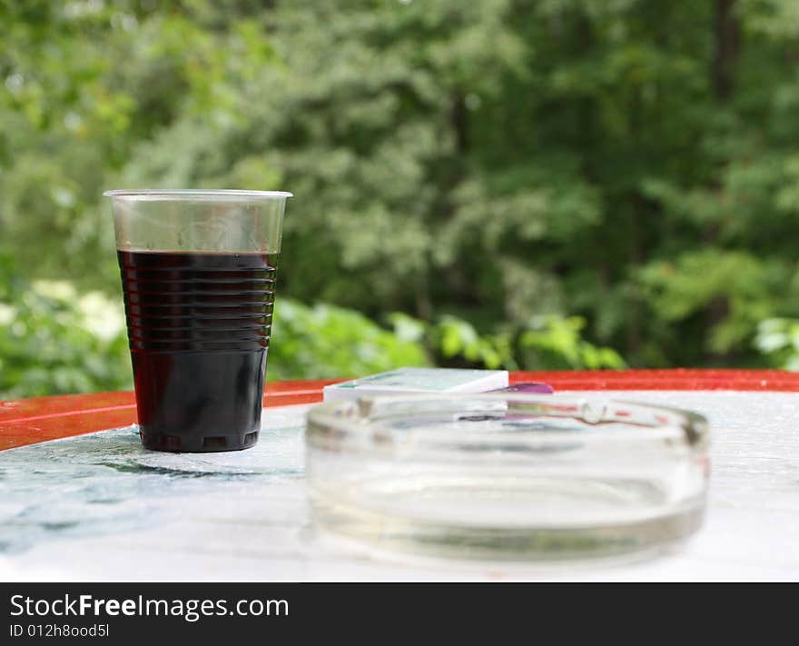 Plastic glass with wine on the table, background from leaf. Plastic glass with wine on the table, background from leaf