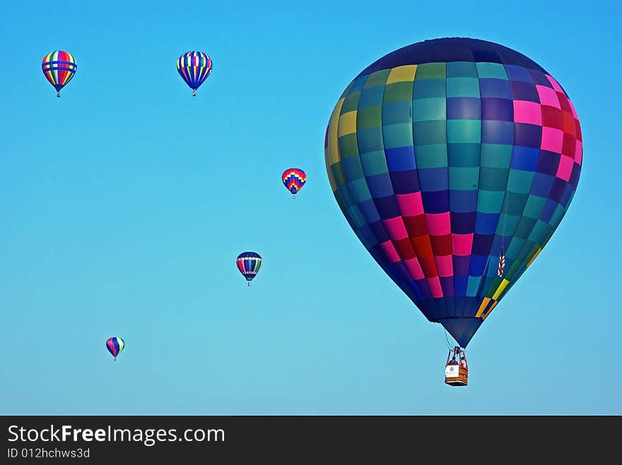 Brightly colored hot air balloon flying just above treetop level. Brightly colored hot air balloon flying just above treetop level