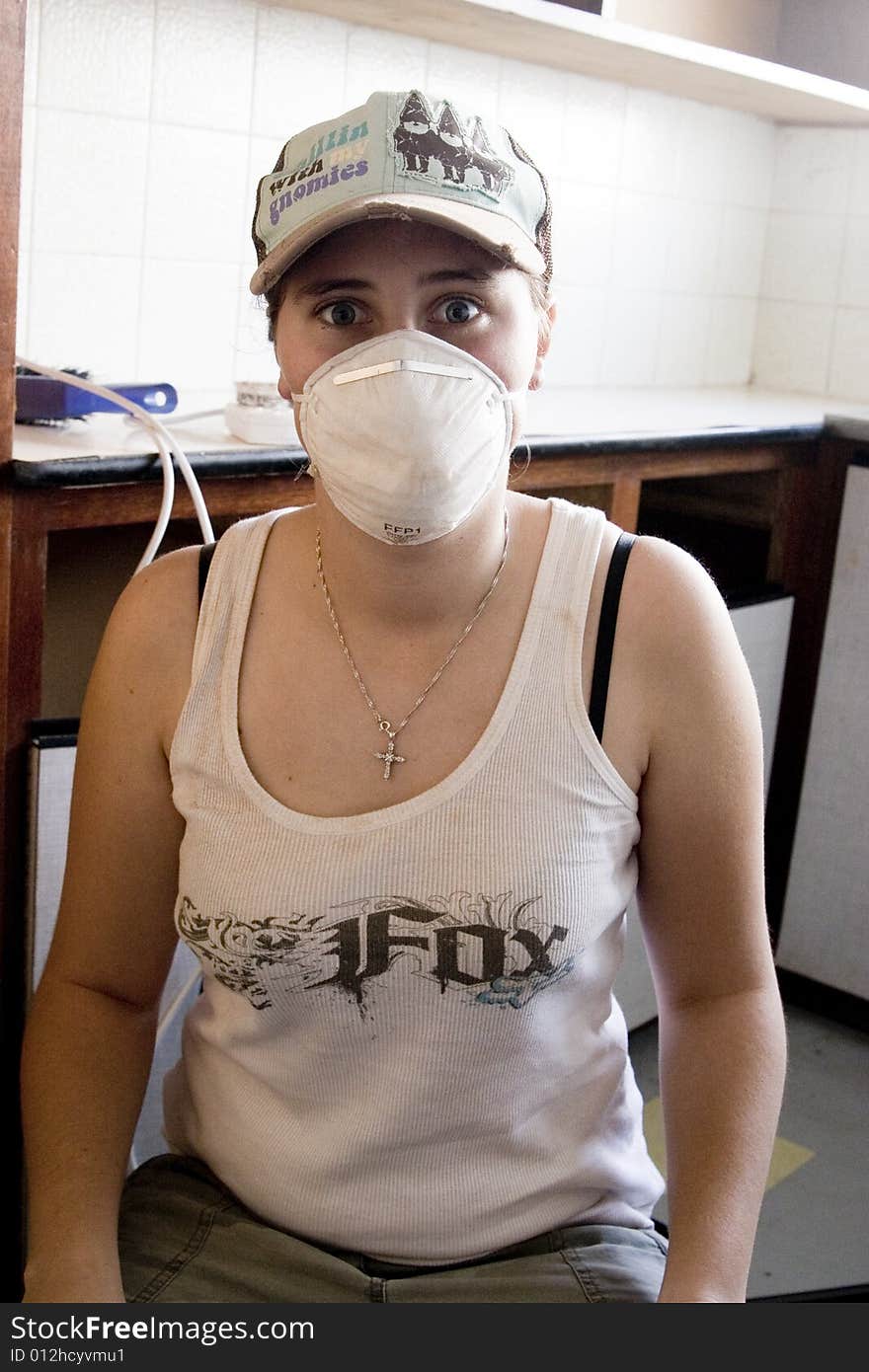 Woman renovating kitchen cupboard wearing a mask. Woman renovating kitchen cupboard wearing a mask