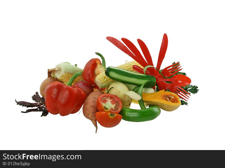 Composition from vegetables - carrots, pepper, a potato, fresh cucumbers and red plastic forks and spoons. Composition from vegetables - carrots, pepper, a potato, fresh cucumbers and red plastic forks and spoons