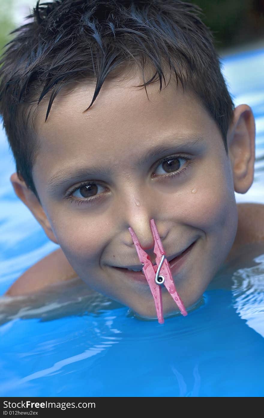 Young boy in pool with clothes peg