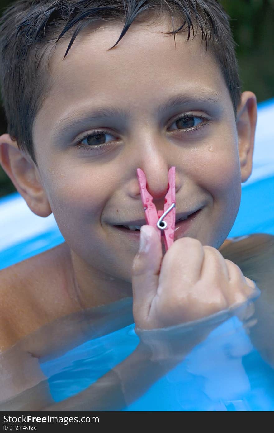 Young boy in pool with clothes peg