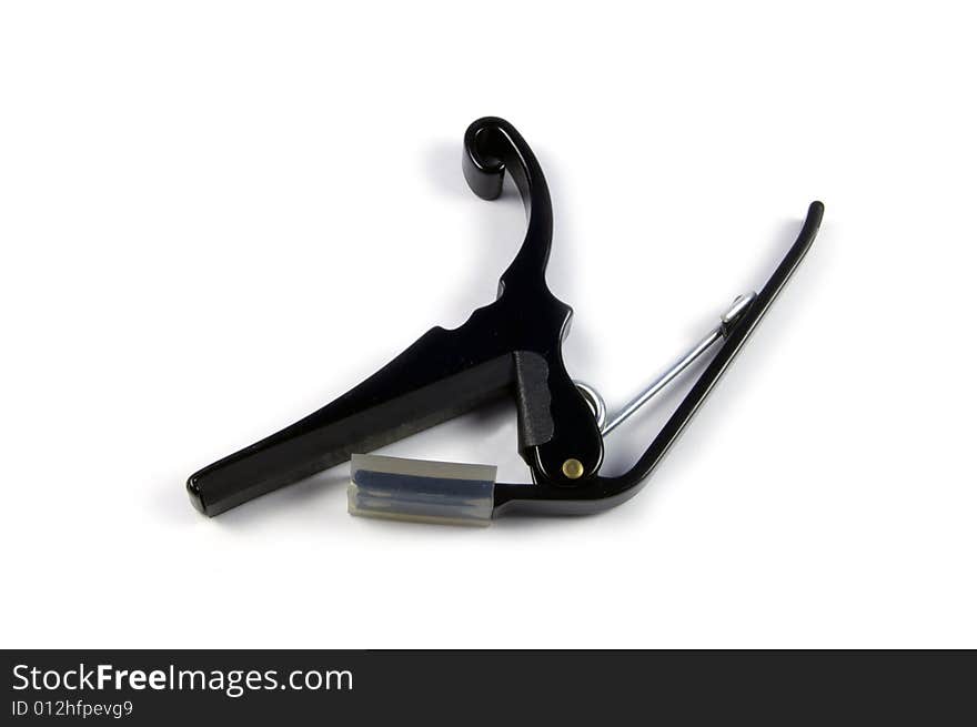 A photograph of a guitar capo against a white background