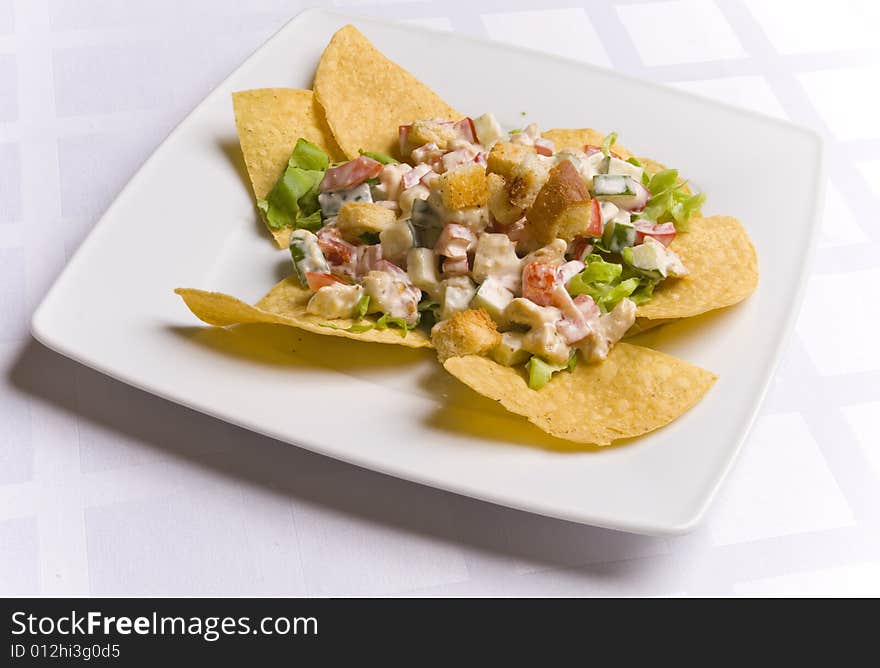 Salad decorated with nachos on white plate