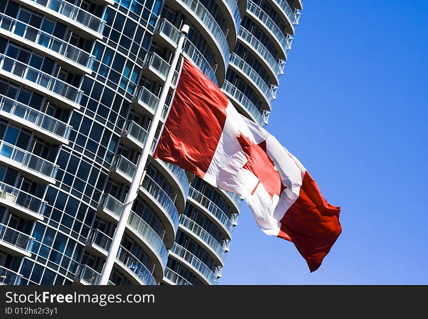 Canadian flag in a blue sky near big building