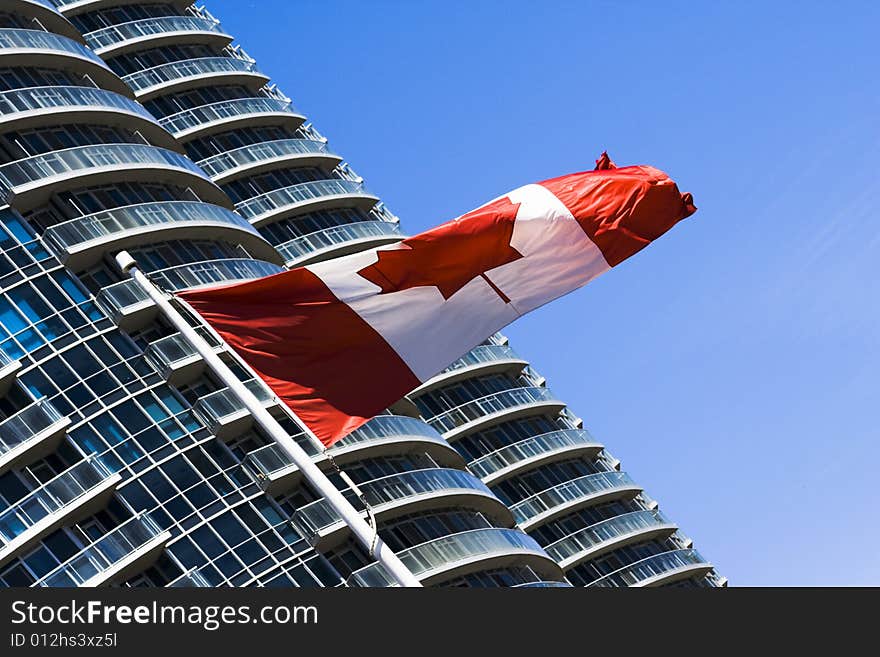 Canadian flag in a blue sky near big building