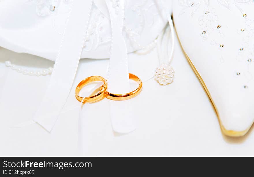 White wedding background with two gold rings, a show and a wedding bag. White wedding background with two gold rings, a show and a wedding bag