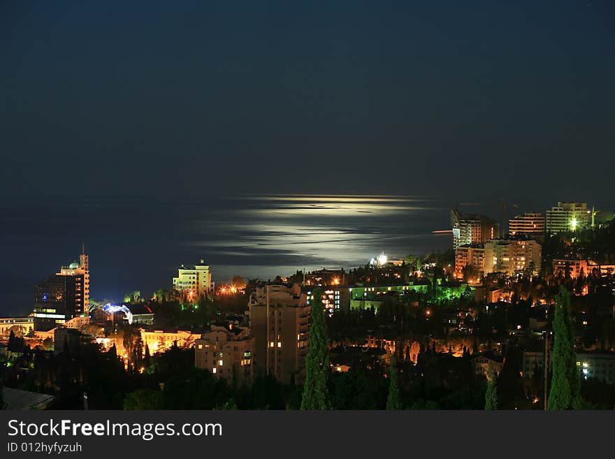 Night city. Houses with illuminated windows and the sea.