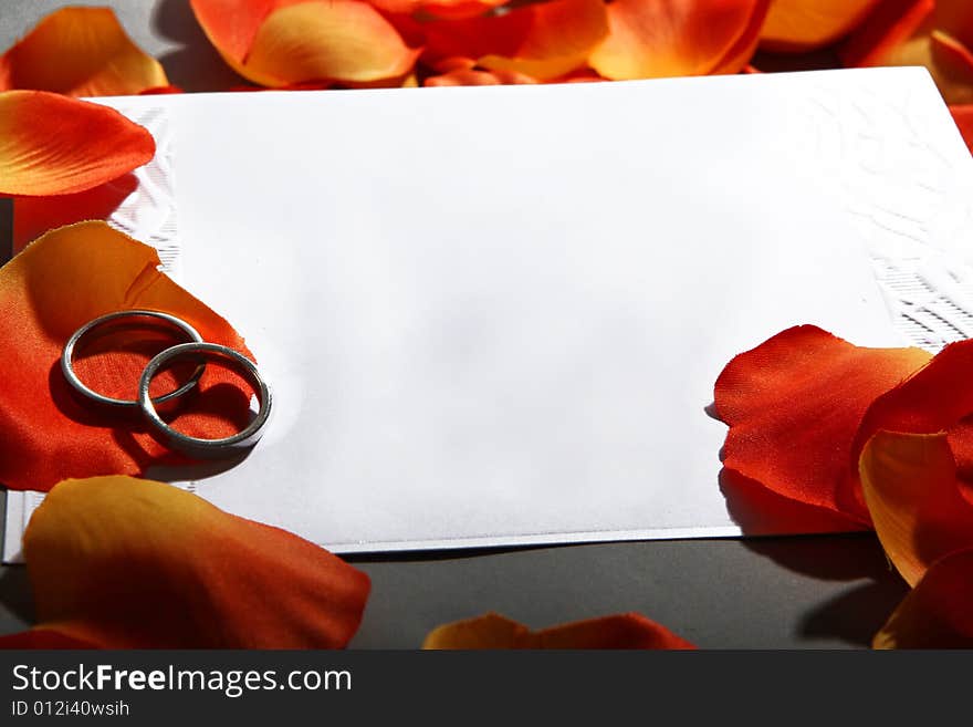 Two wedding rings and an invitation to wedding