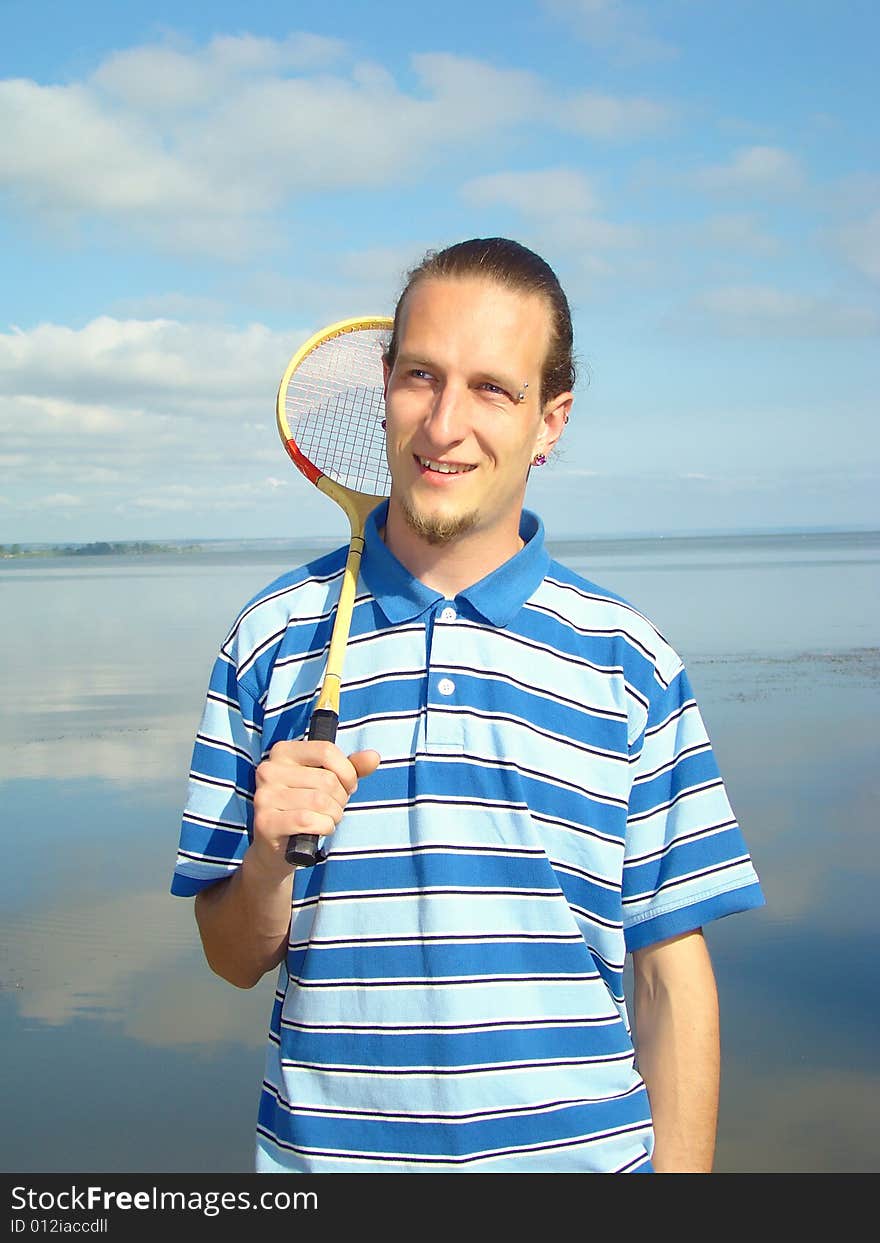 Young adult man with a racket for a badminton on the riverside. Rest on fresh air. Young adult man with a racket for a badminton on the riverside. Rest on fresh air.