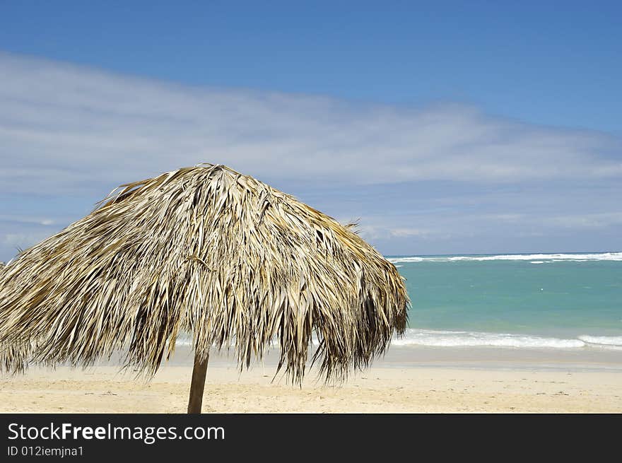 Parasol made out of palm leafs on beach.